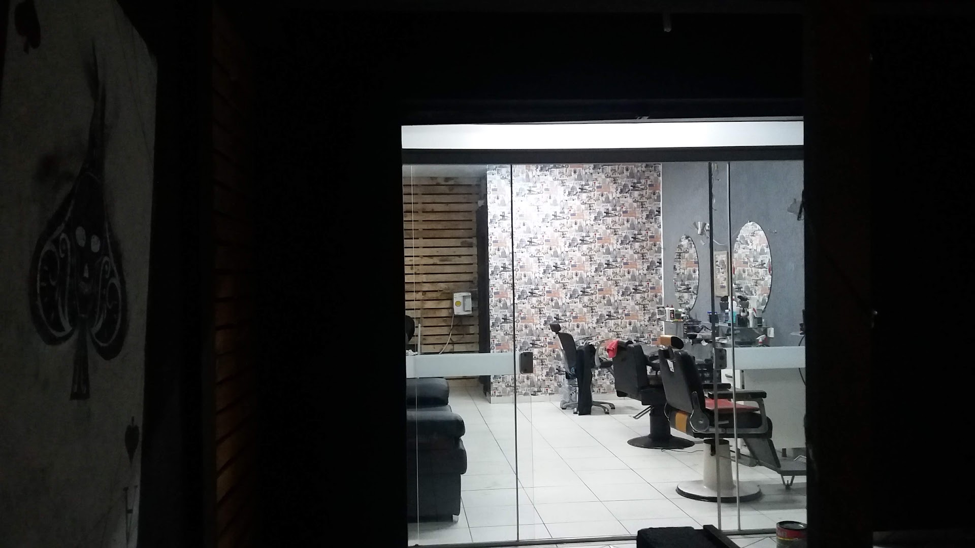 Cadeiras de barbeiro e naipe de espadas na parede dentro da Barbearia Az De Espadas